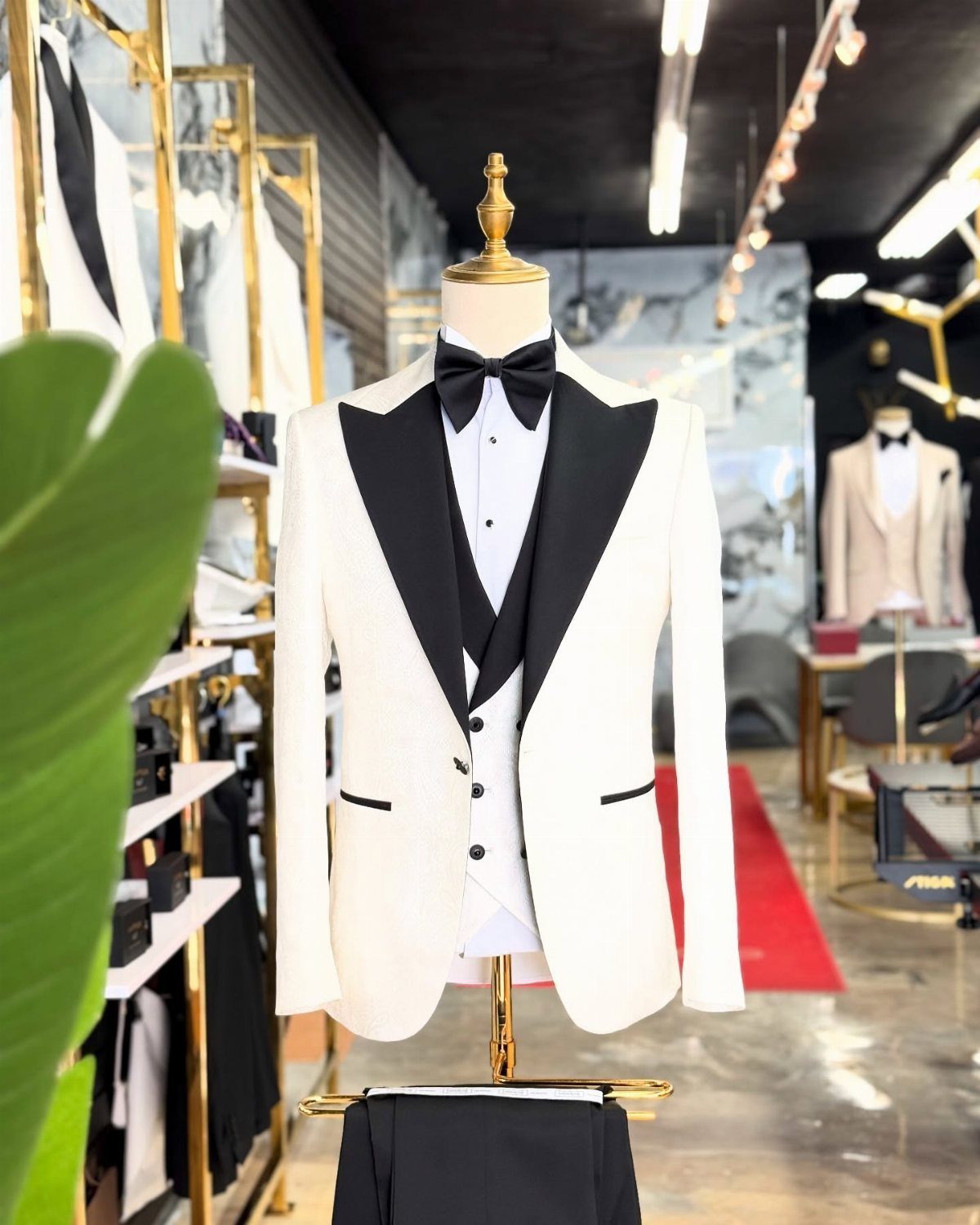 White tuxedo jacket with black lapels and bow tie on a gold mannequin.