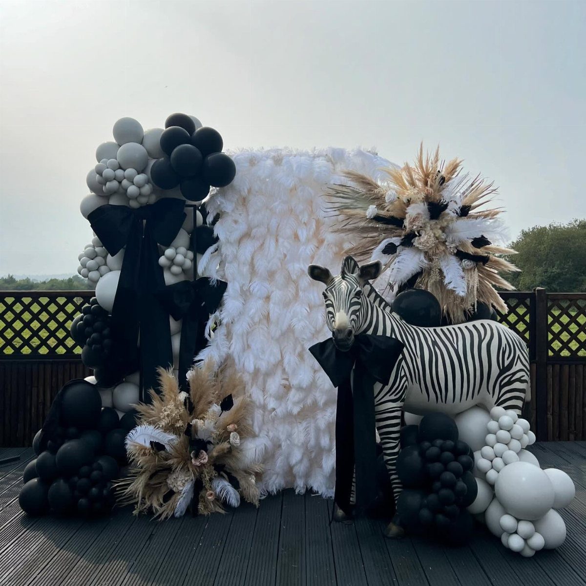 Zebra statue with black bow surrounded by black and white balloons and feathers.