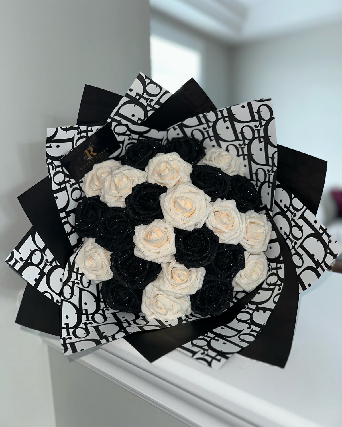 Bouquet of black and white roses wrapped in patterned black and white paper.
