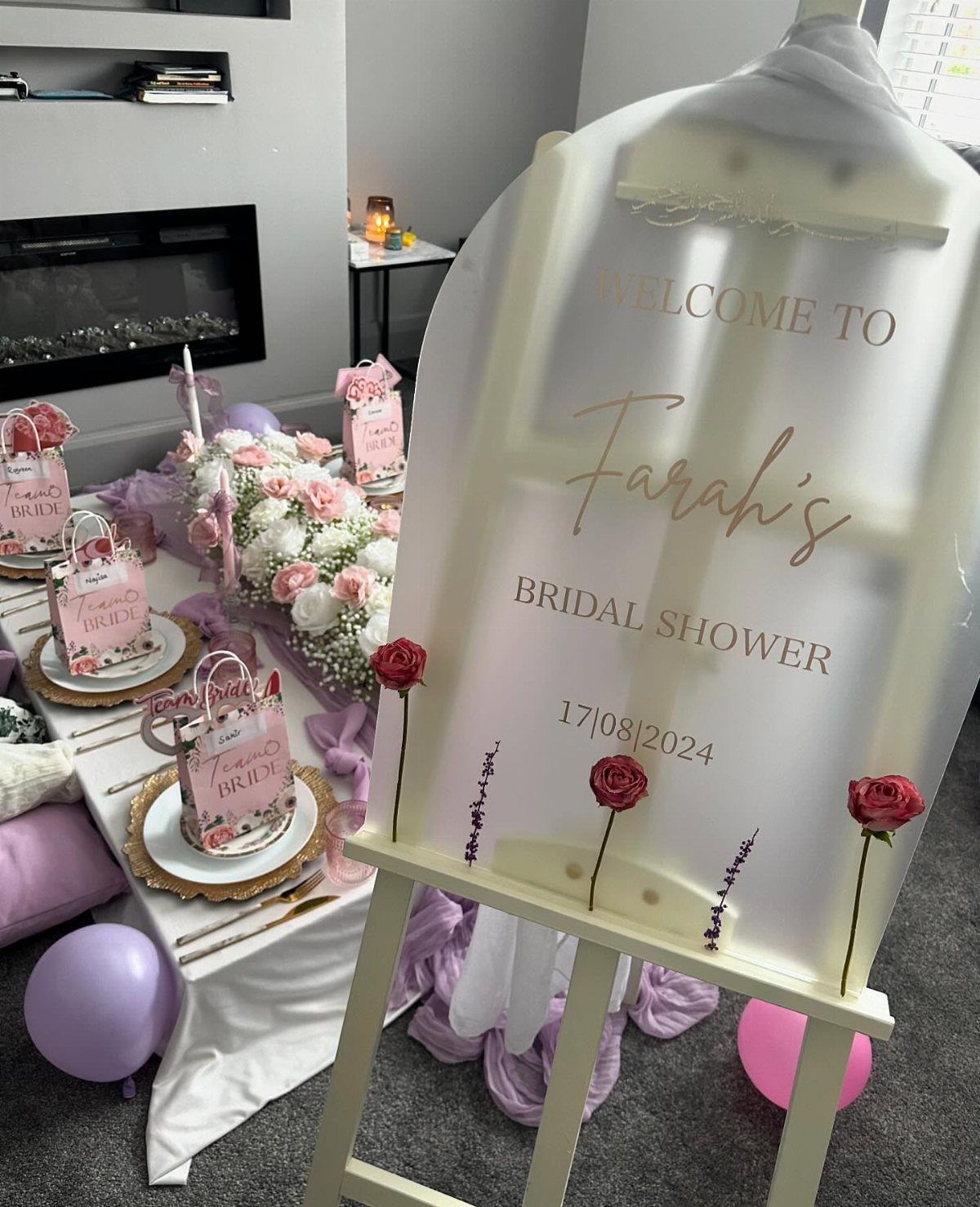 Clear acrylic bridal shower welcome sign on an easel with red rose accents.