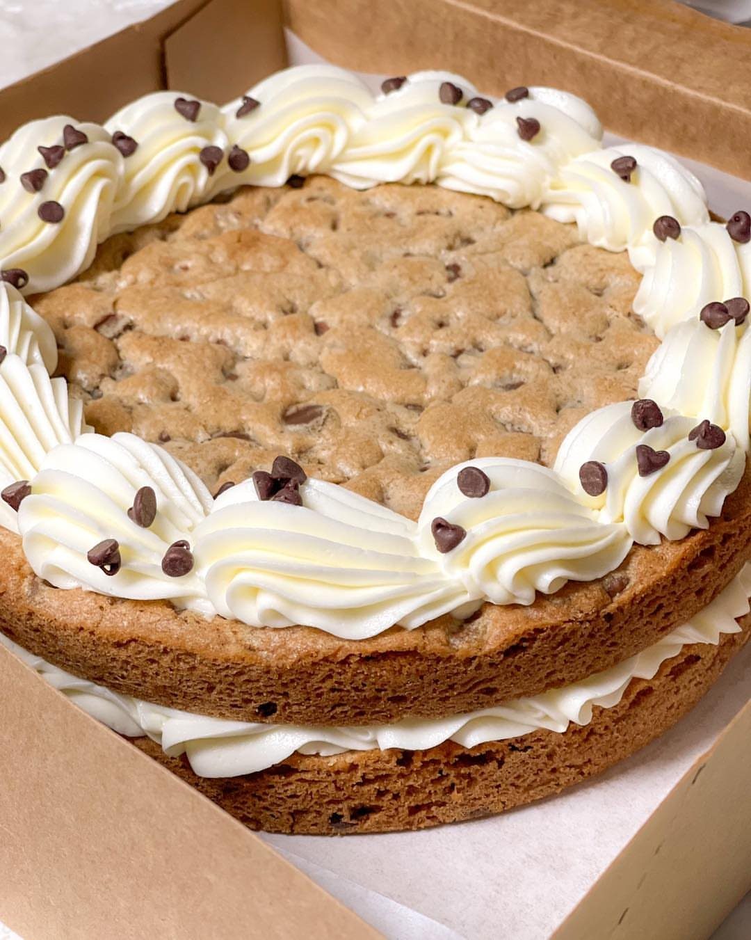 Two-layer chocolate chip cookie cake with white buttercream filling and frosting swirls.