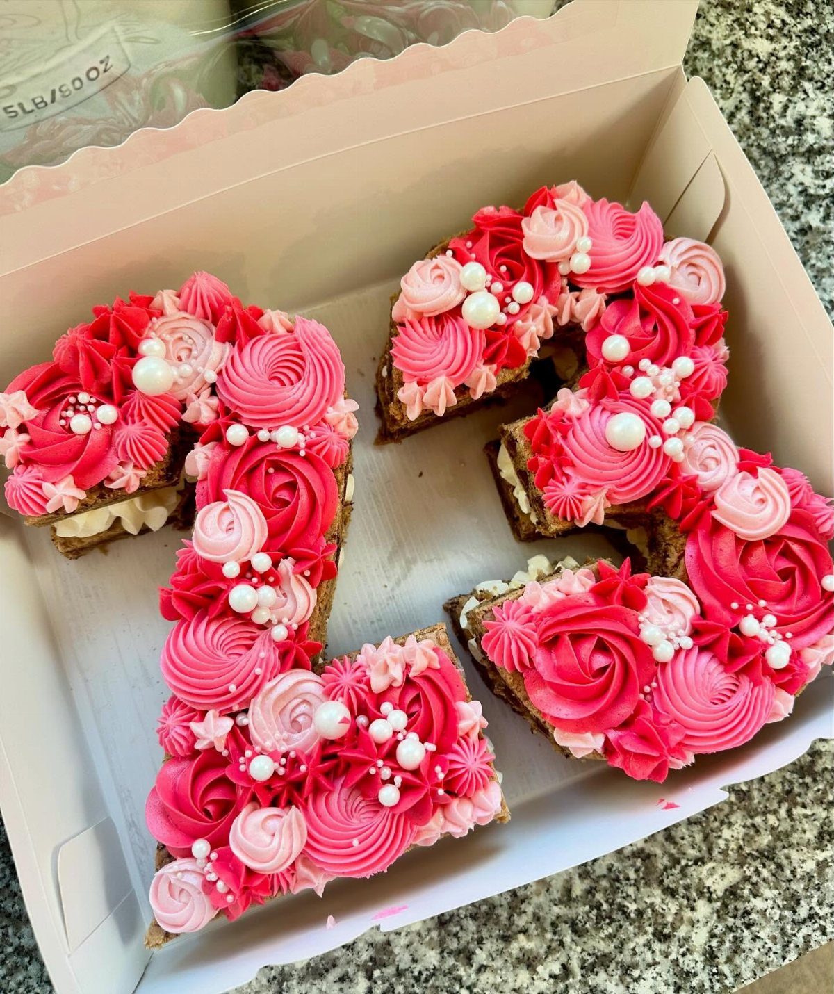 Number 23 cookie cake with pink and red frosting swirls and white pearls