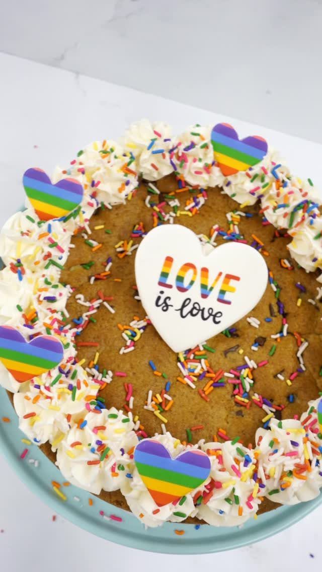 Rainbow sprinkle cookie cake with whipped cream and colorful heart-shaped cookies.