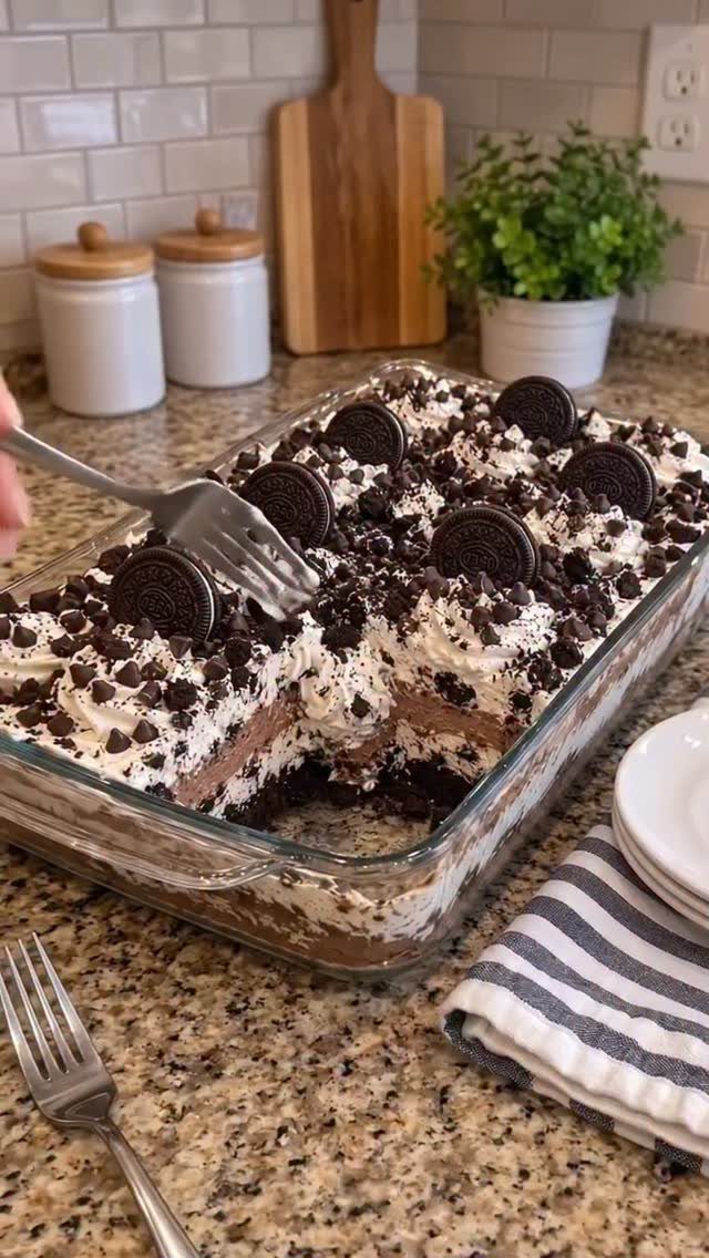 Layered Oreo dessert in a glass dish topped with whipped cream and cookies
