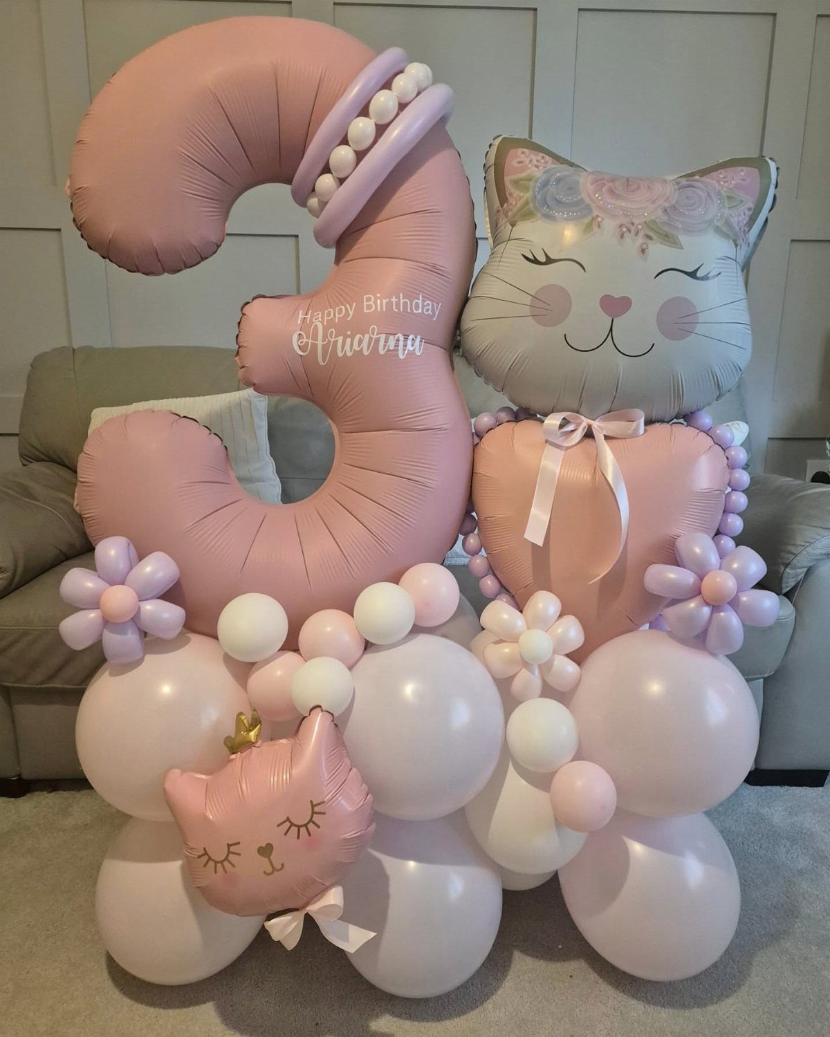 Balloon arrangement with a large pink number three and cat-shaped foil balloons.