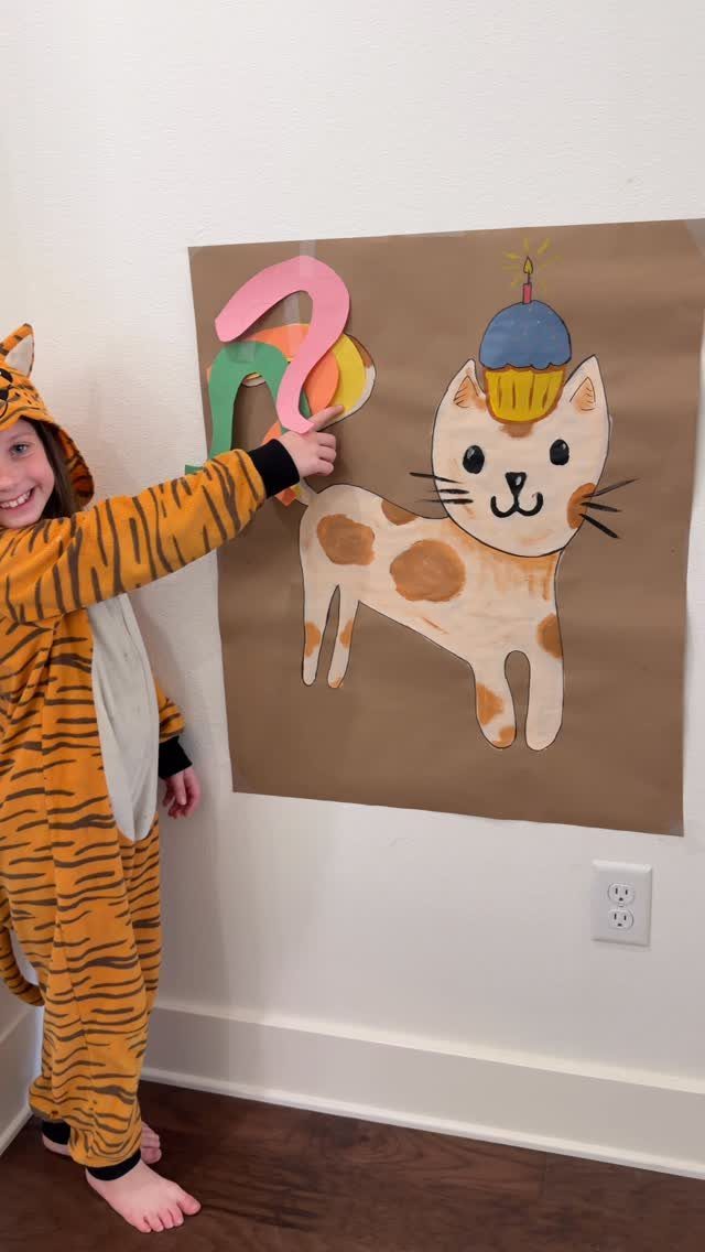 Girl in tiger costume pinning a tail on a cat poster for a party