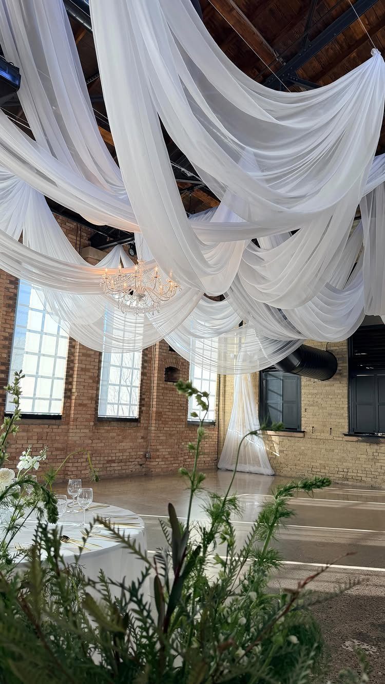 White cascading ceiling drapes with a crystal chandelier in a brick venue