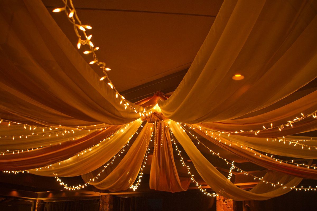 White and peach fabric drapes radiating from a center point with string lights.