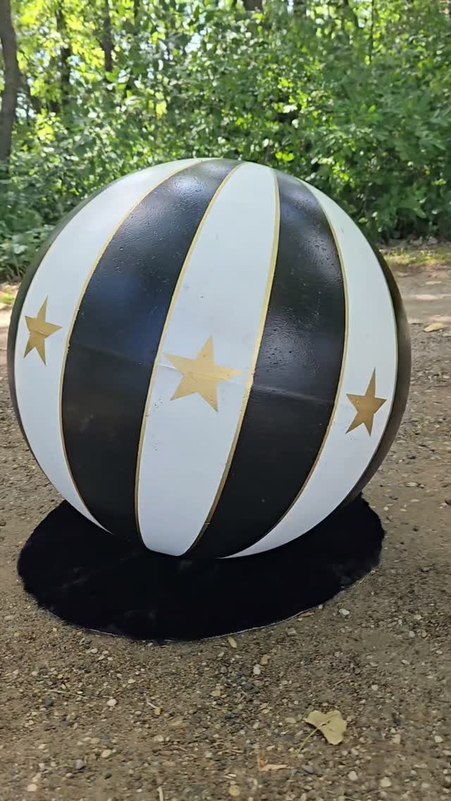 Striped circus ball decoration with gold stars on a black base outdoors