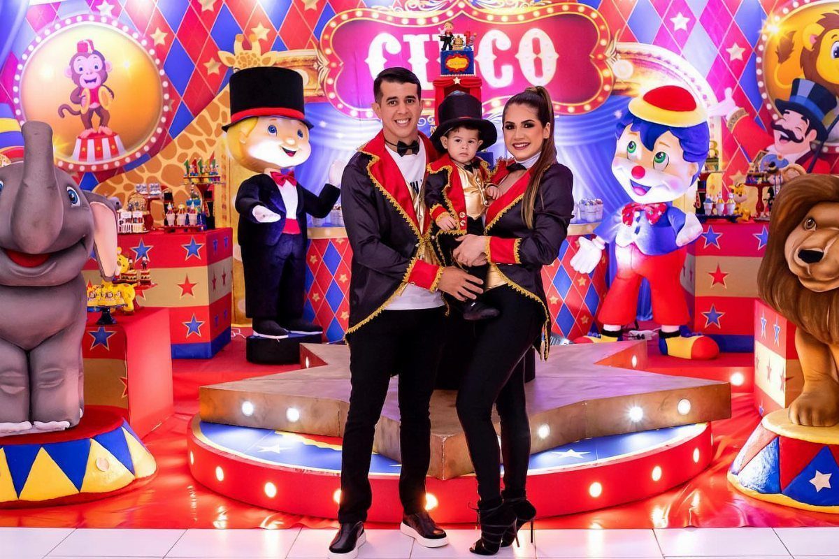 Family in ringmaster costumes posing before a colorful circus themed party backdrop