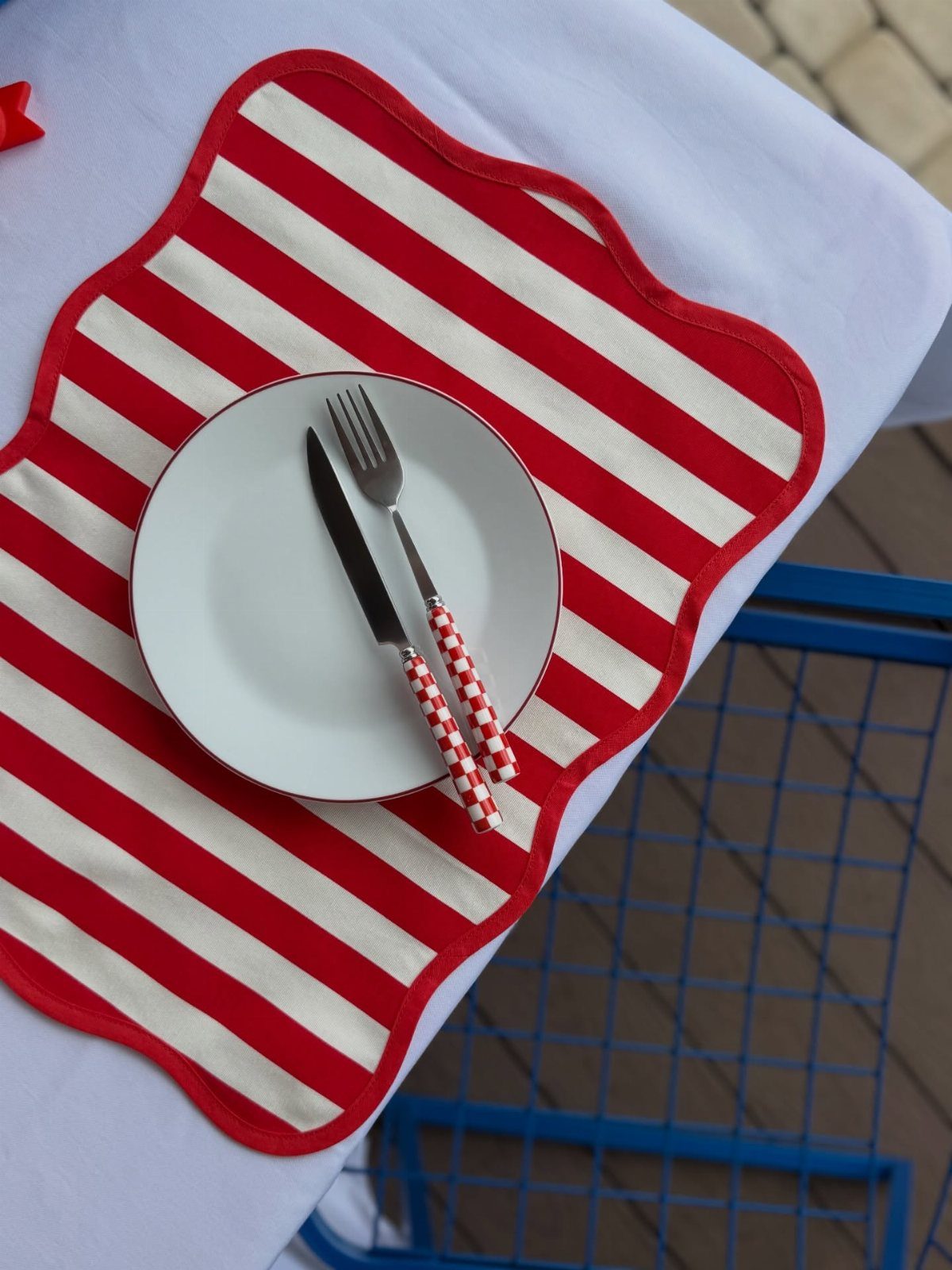 Red and white striped placemat with a white plate and checkered cutlery.