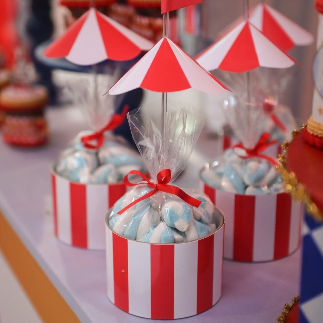 Circus themed party favors in red and white striped containers with tent toppers.