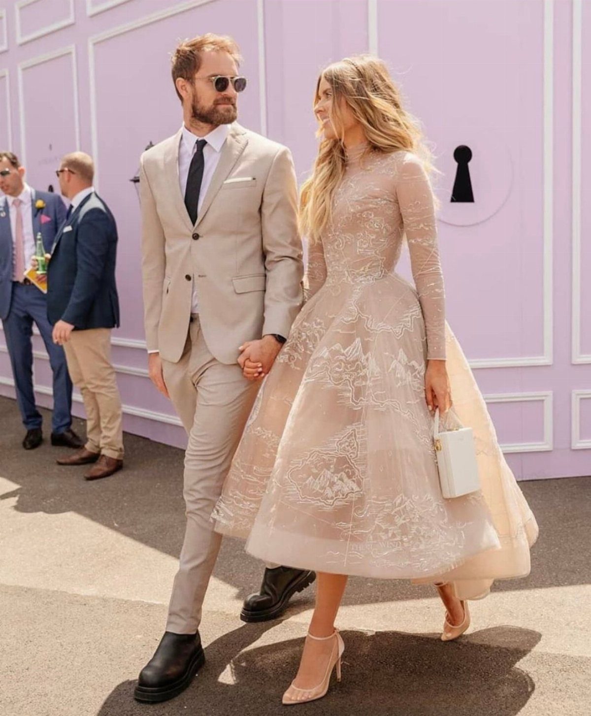 Couple walking, woman wearing a champagne lace tea-length wedding dress and man in beige suit