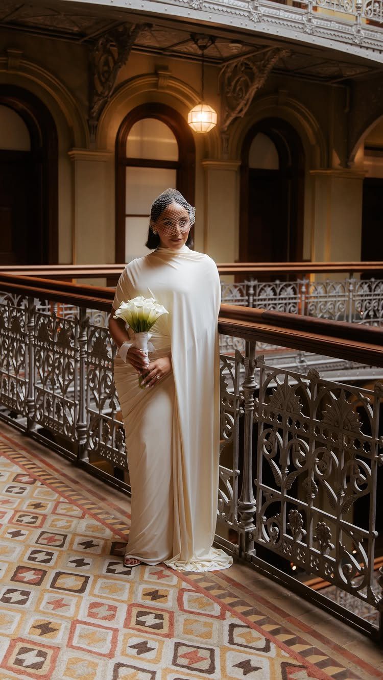 Woman in a white saree holding white flowers in a grand hall