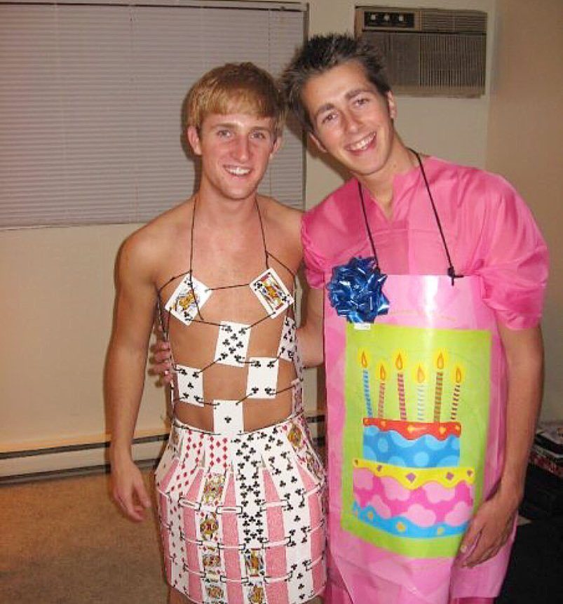 Two men wearing creative homemade costumes made from playing cards and gift wrap.