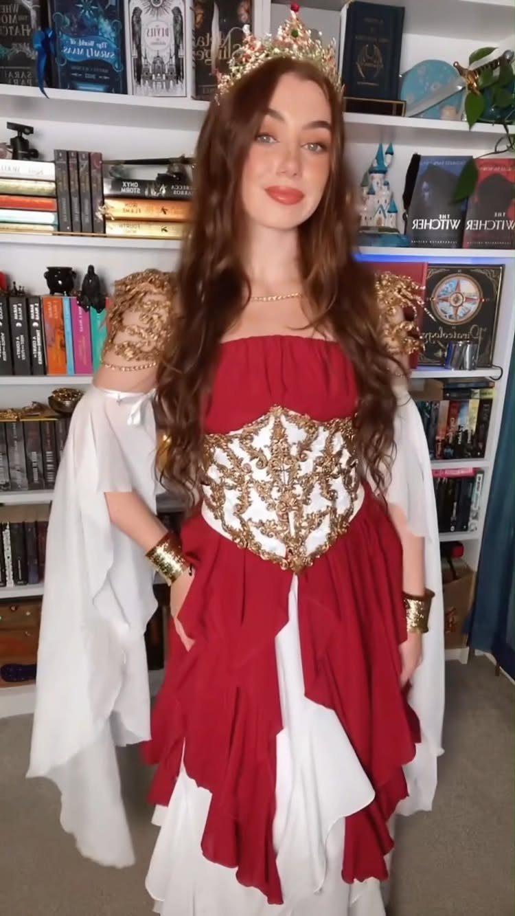 Woman wearing a red and white fantasy gown with a gold crown and jewelry.
