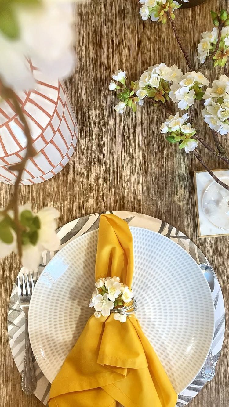 Yellow fabric napkin with a white floral napkin ring on a white plate