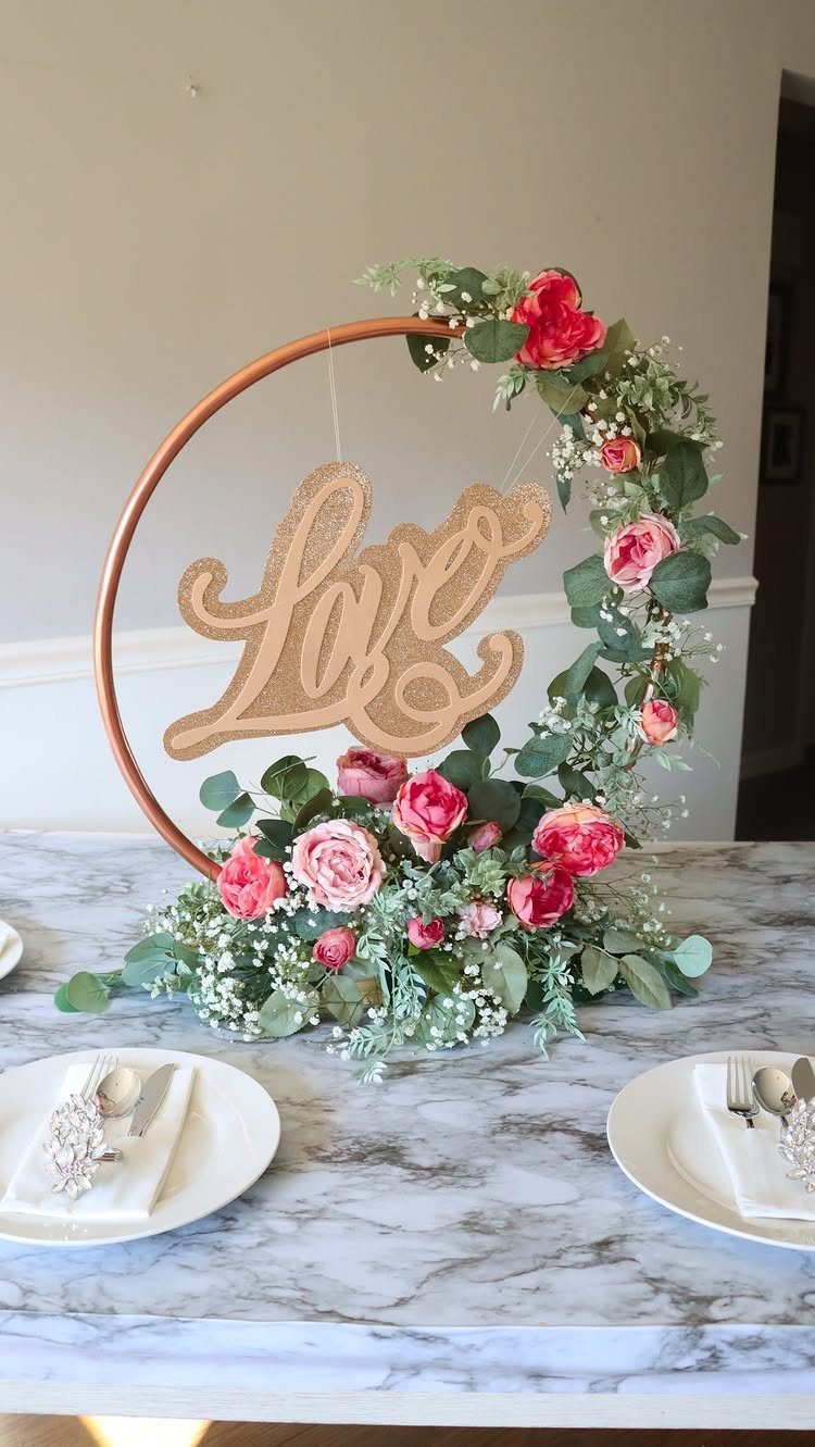 Copper floral hoop centerpiece with a gold Love sign on a marble table