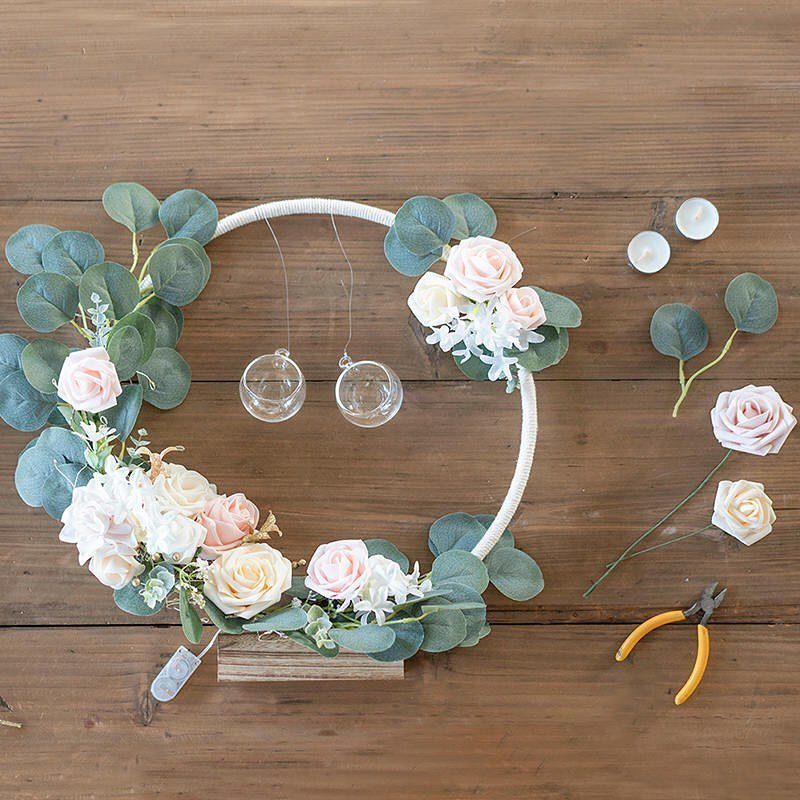 White circular hoop wreath with pink roses and eucalyptus on wooden background