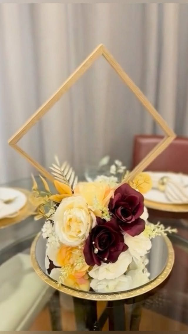 Floral centerpiece with red and white roses and a gold diamond frame.