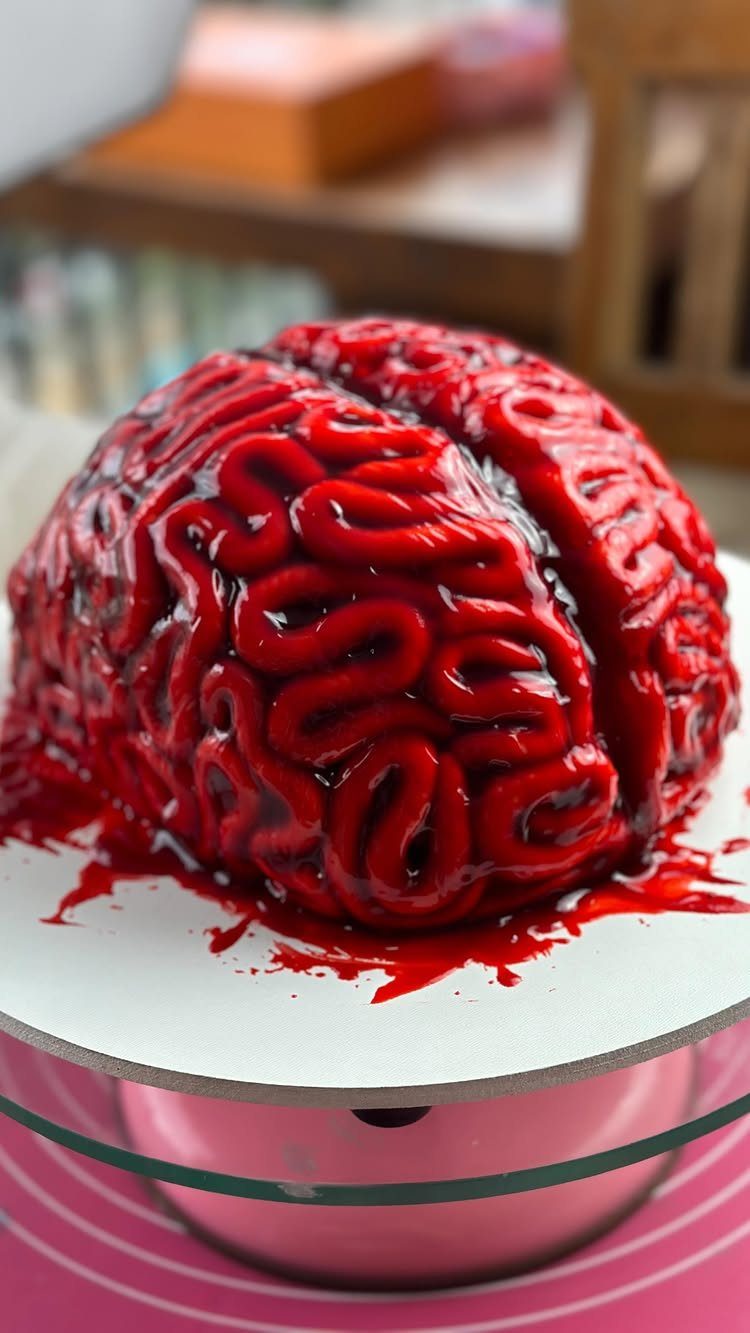 Red brain cake with glossy glaze on a white cake stand