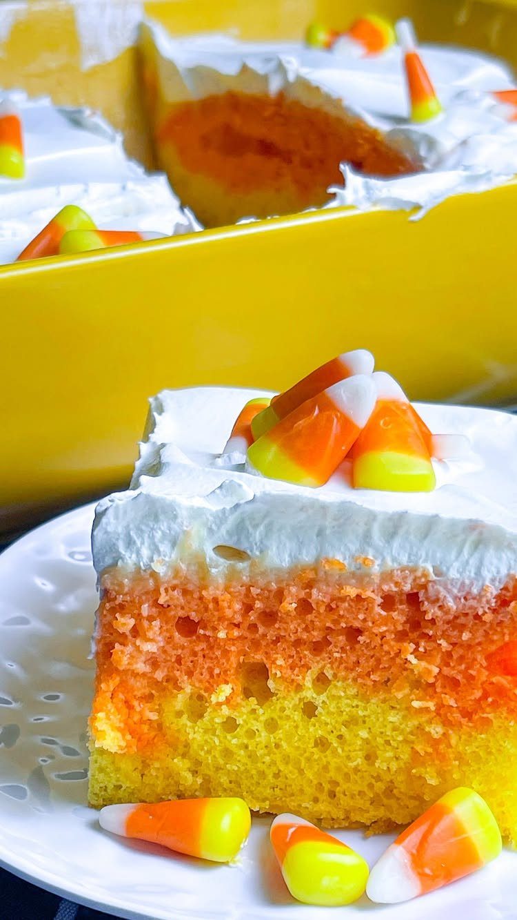 Layered yellow, orange, and white cake topped with frosting and candy corn pieces.