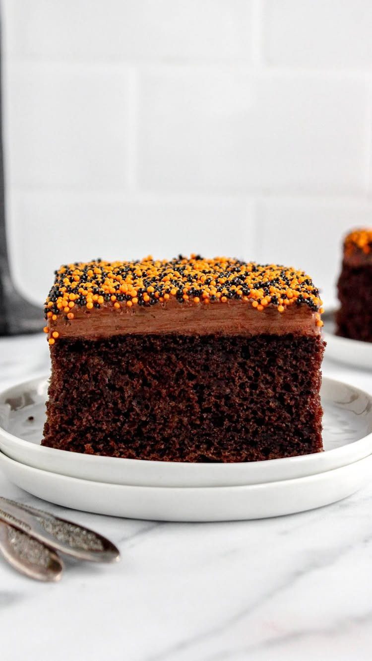 Chocolate cake slice with chocolate frosting and orange and black Halloween sprinkles.