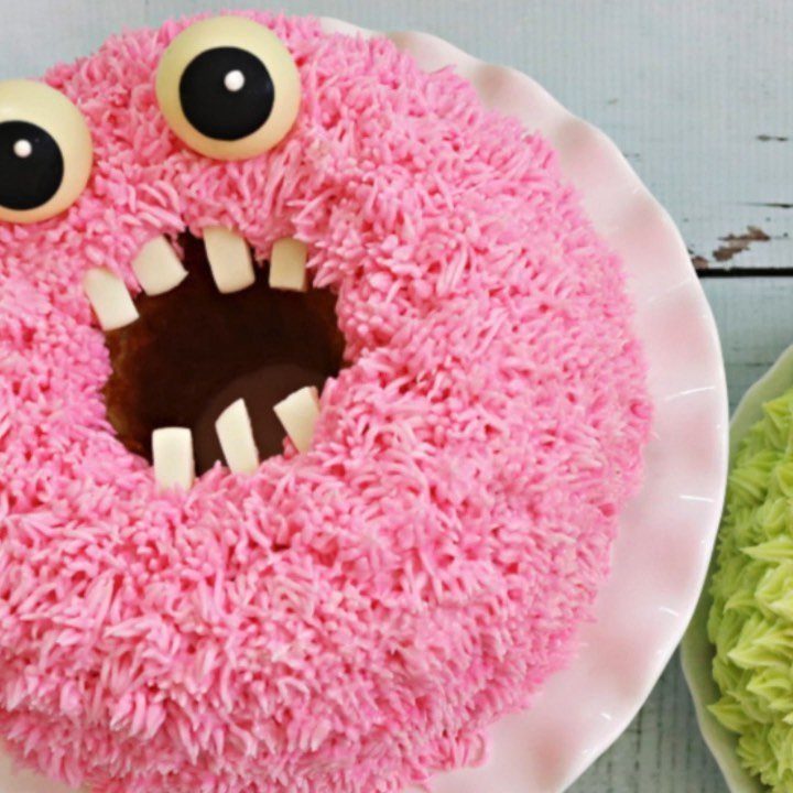 Pink fuzzy monster mini bundt cake with candy eyes and white teeth.