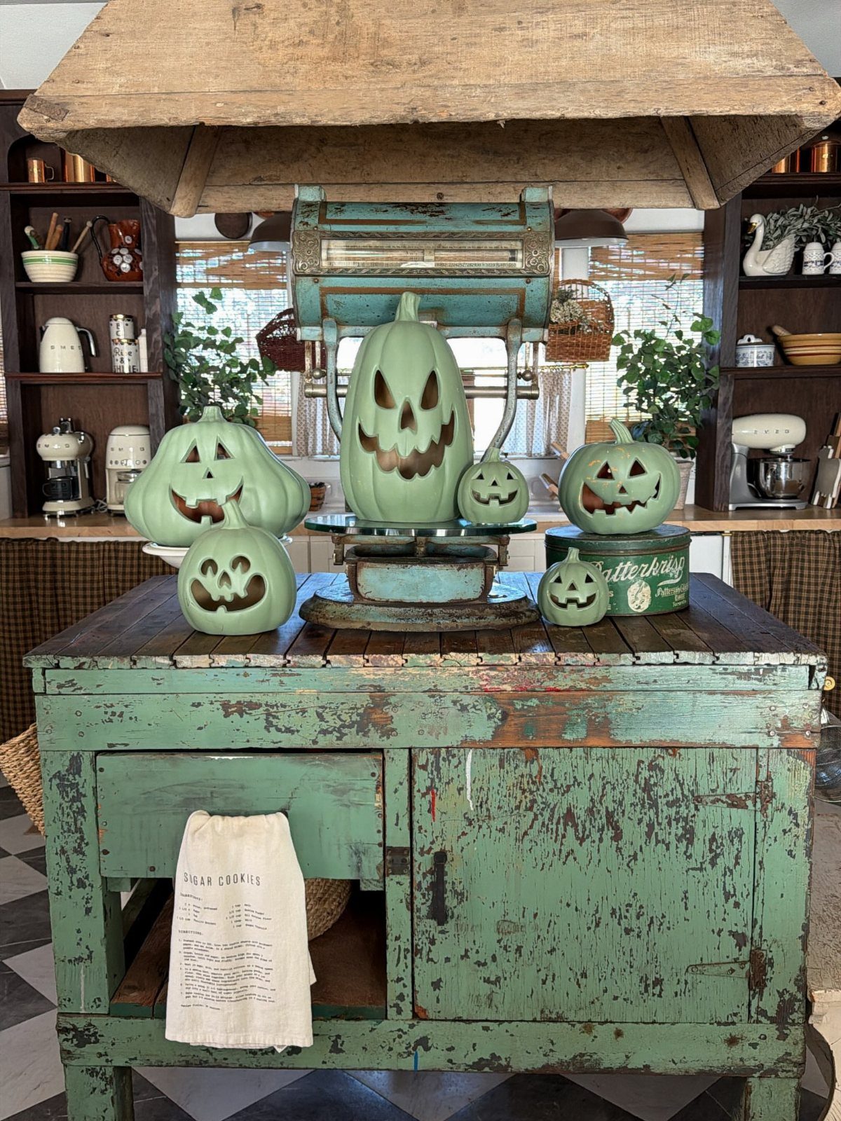 Light green carved pumpkins on a distressed teal vintage wooden kitchen island.