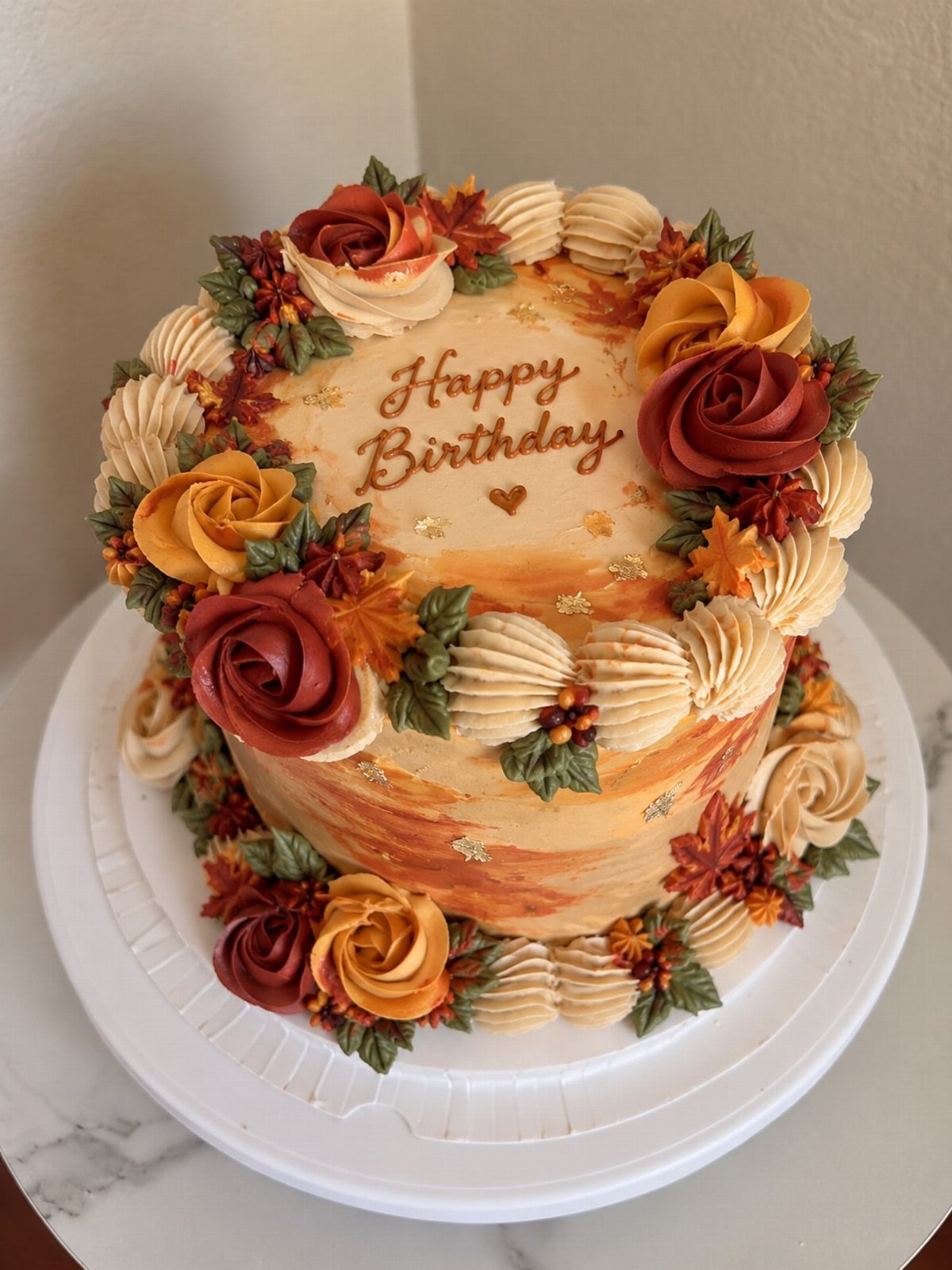 Fall themed birthday cake with orange frosting and autumn-colored buttercream roses.
