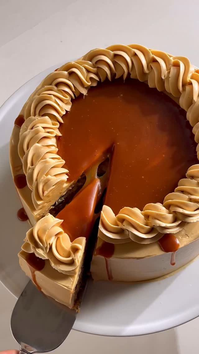 Caramel cake with piped frosting swirls and a glossy glaze on white plate
