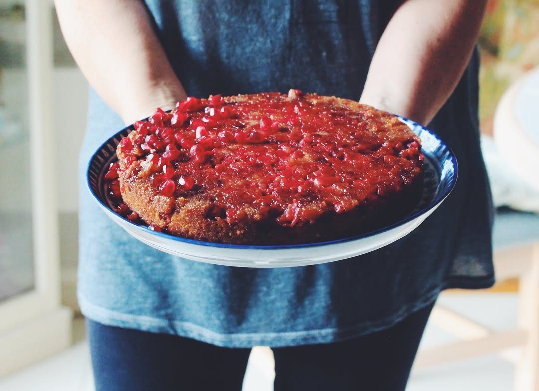 Cranberry upside-down cake with red berries on a blue and white plate.