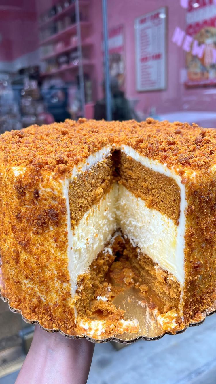 Layered pumpkin cheesecake with a crumb coating and a slice removed.