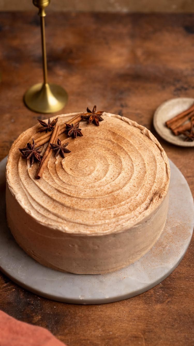 Brown frosted cake with cinnamon swirls and star anise on a wooden table