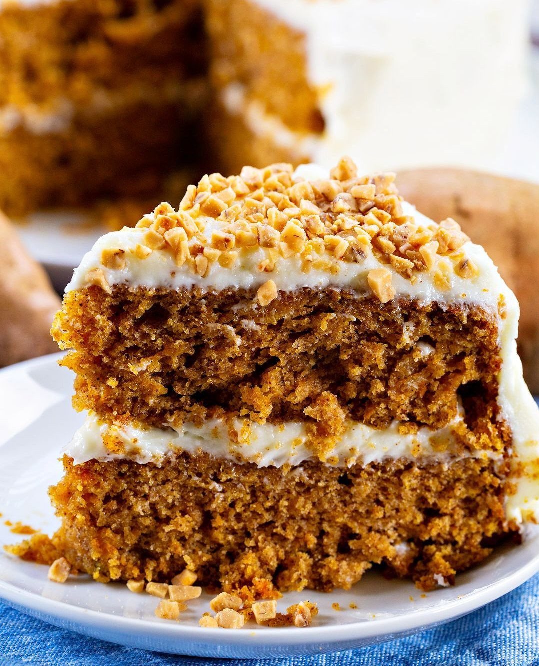 Slice of two-layer sweet potato cake with white frosting and chopped nuts.