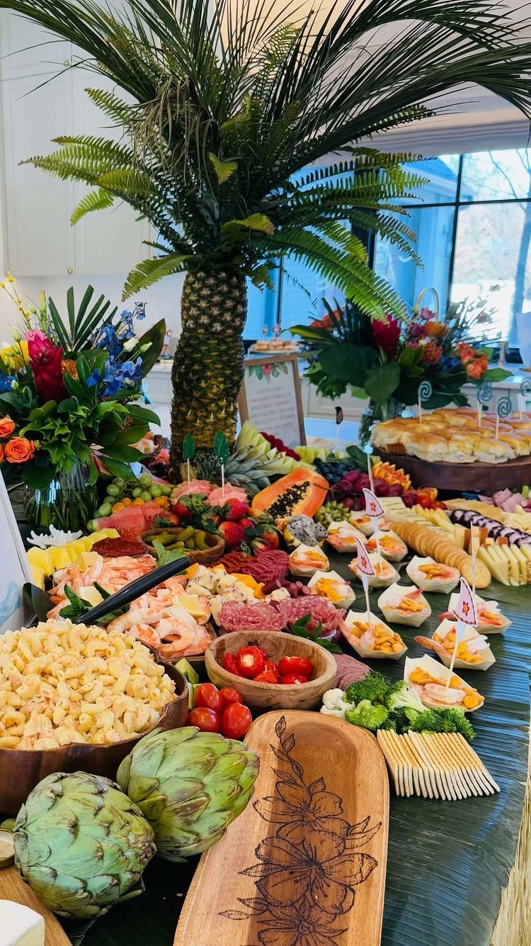 Tropical food spread with a pineapple palm tree centerpiece and vibrant island decor.