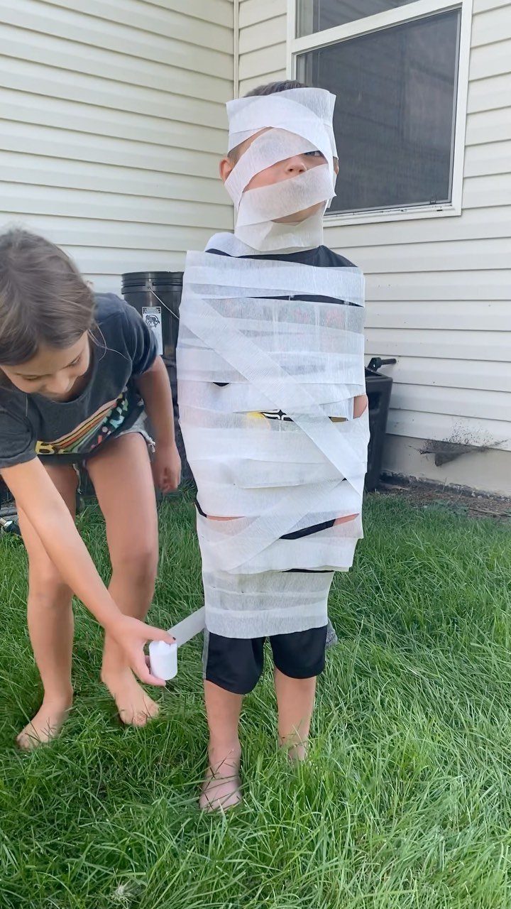 Girl wrapping a boy in toilet paper for a mummy wrap party game.