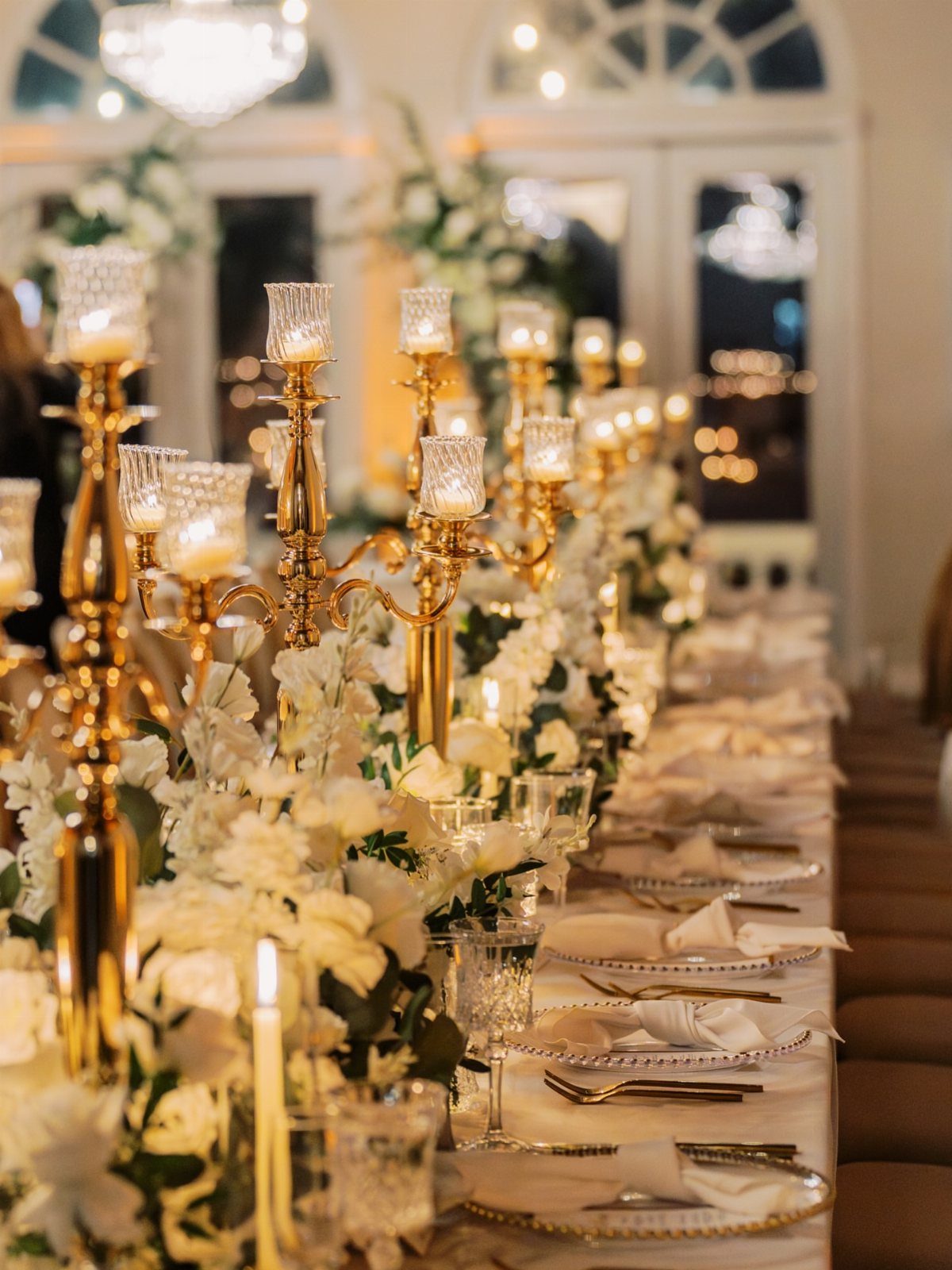 Gold candelabra centerpieces with white orchids on a formal party dining table.