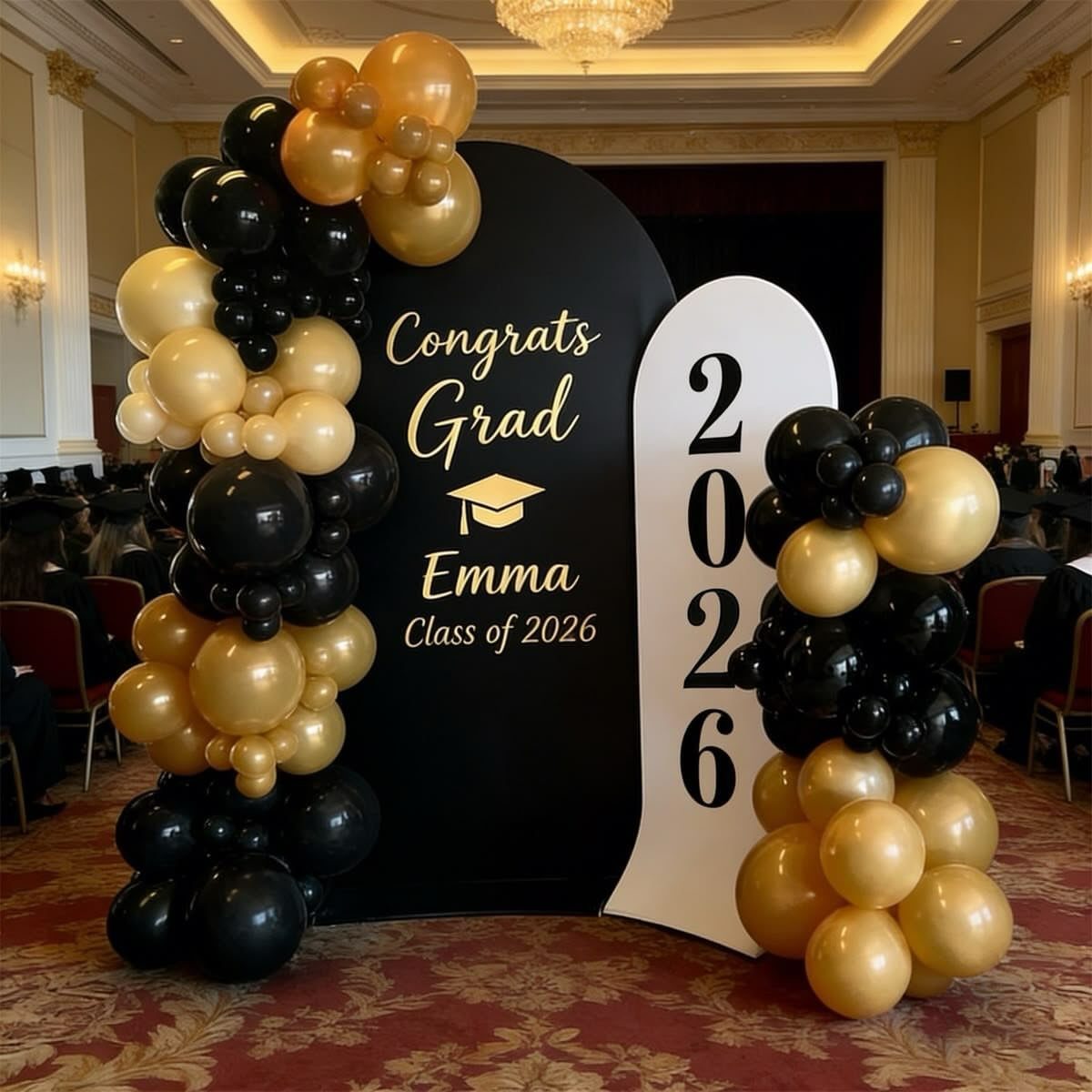 Graduation photo booth with black and white backdrops and gold and black balloons.
