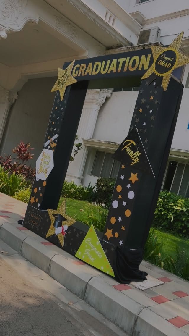 Black graduation photo booth frame with gold stars and graduation text outdoors