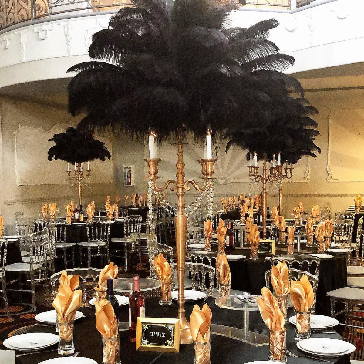 Gold candelabra topped with black ostrich feathers as a centerpiece on a banquet table