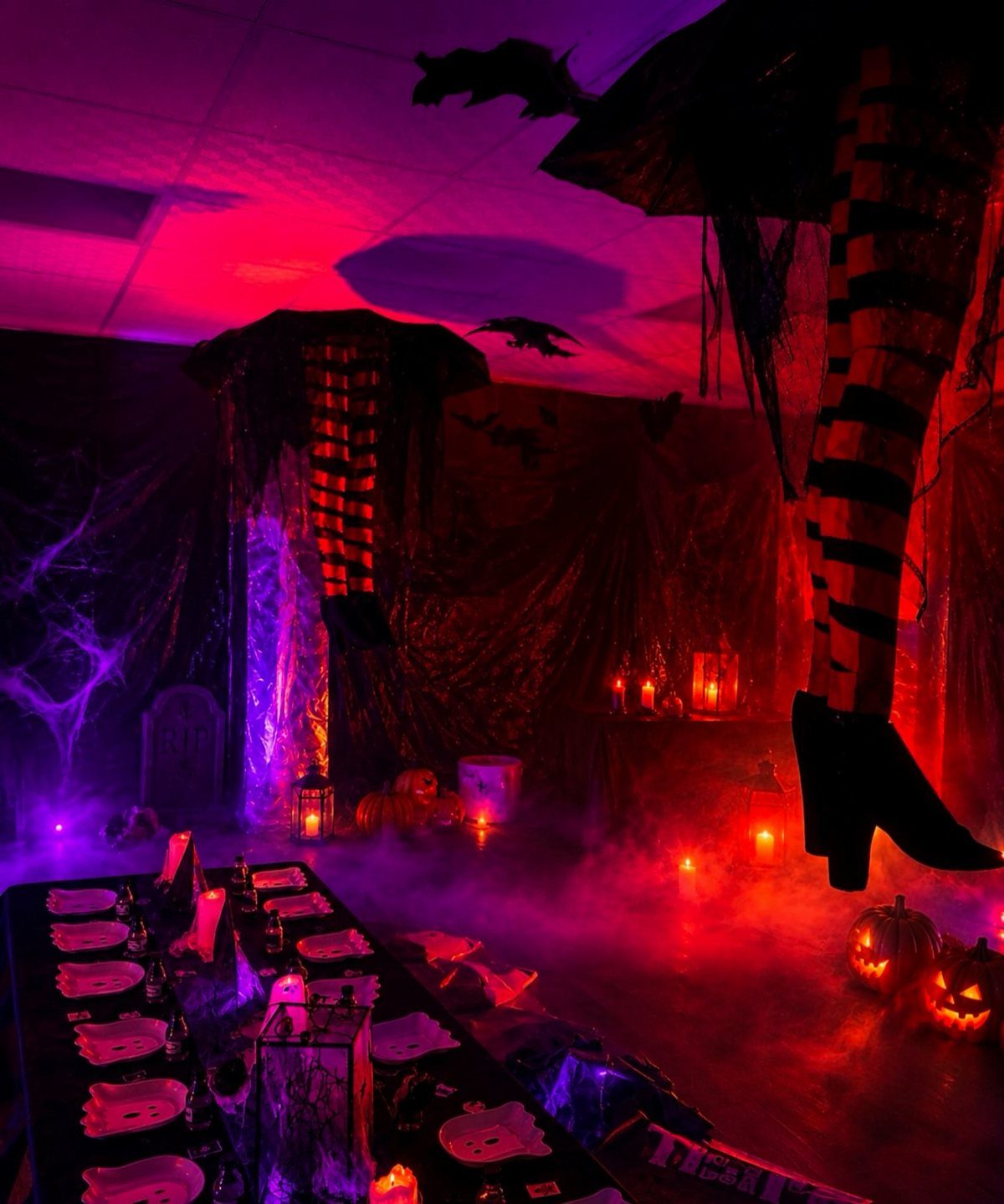 Long table with black tablecloth and plates in a foggy, red-lit Halloween room.