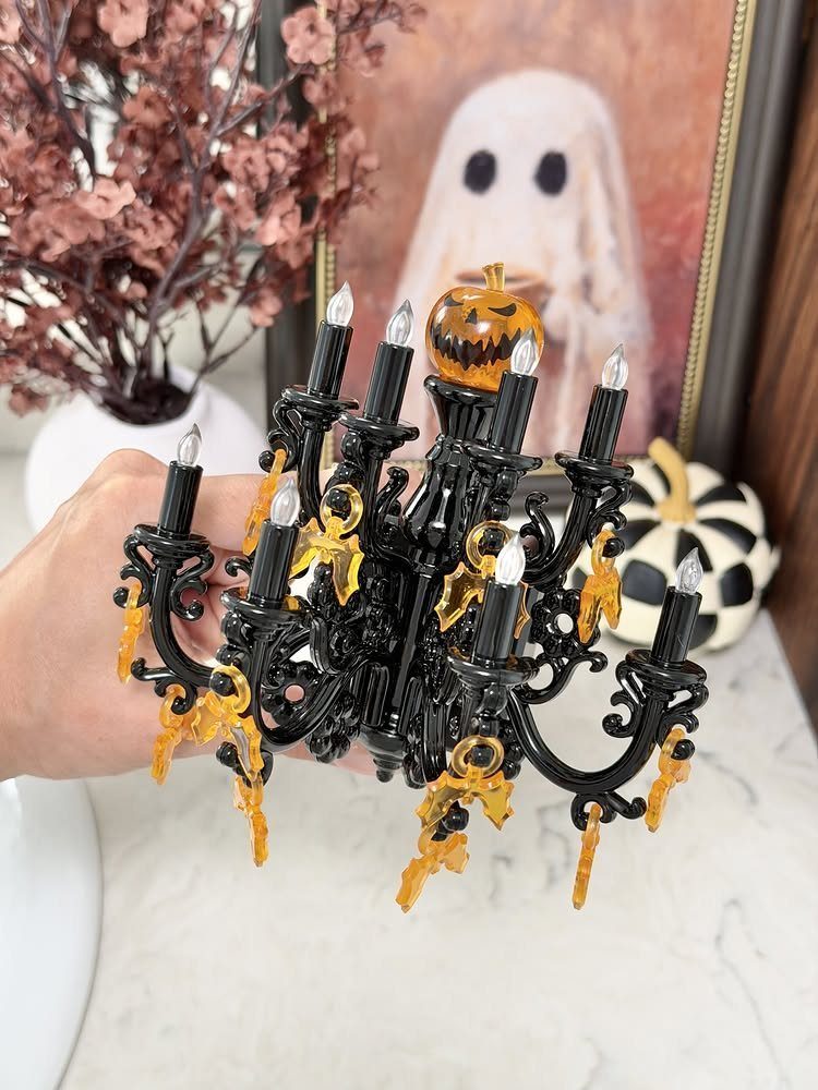 Black ornate candelabra with orange accents and a small pumpkin on top.