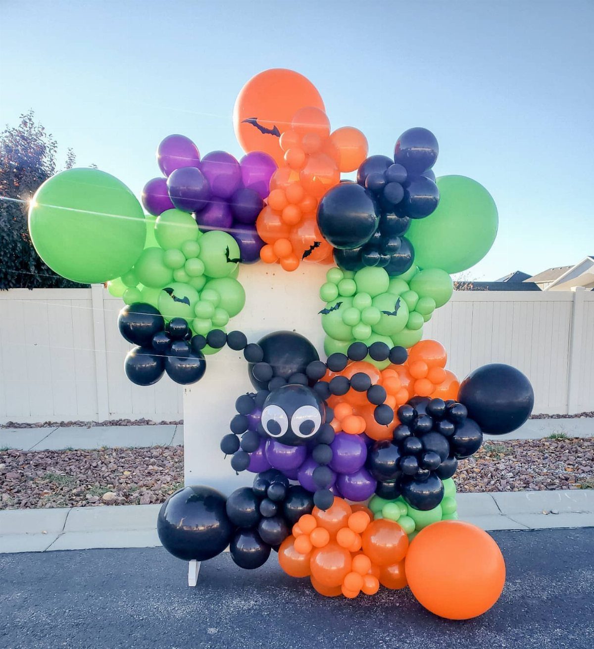 Spider balloon sculpture with black, orange, purple, and green balloons and bat accents.