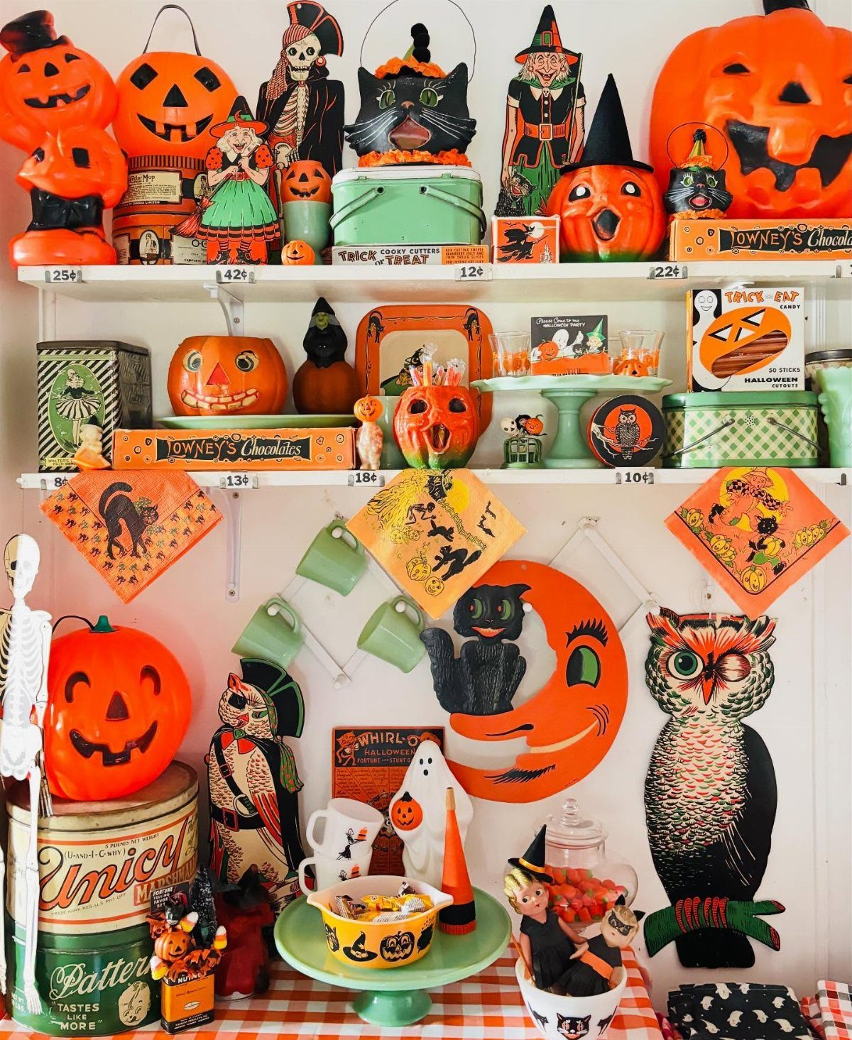 Vintage Halloween decorations including jack-o'-lanterns, black cats, and owls on white shelves.