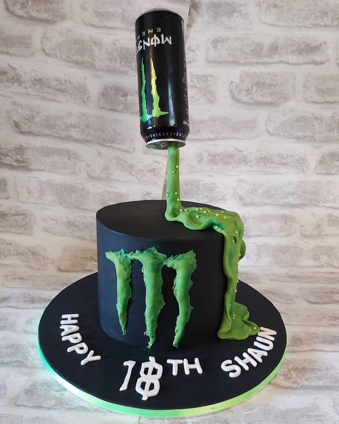 Black birthday cake with a floating Monster Energy can pouring green frosting.
