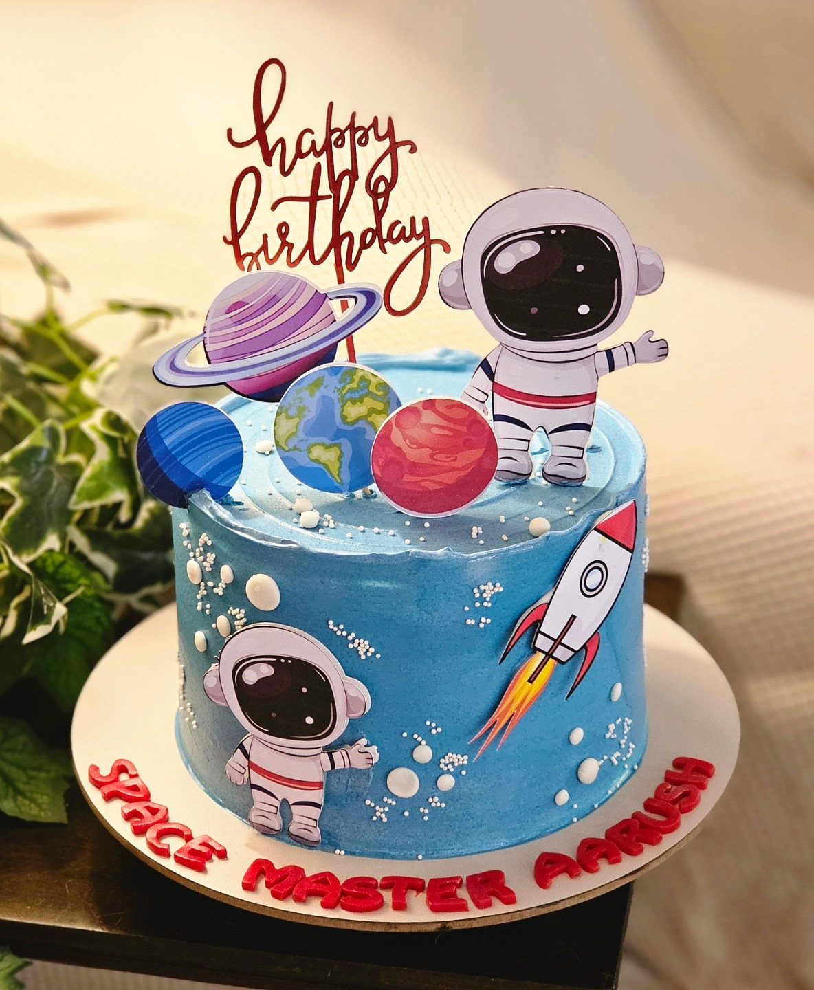 Blue space-themed birthday cake with astronaut, planets, and rocket ship decorations.