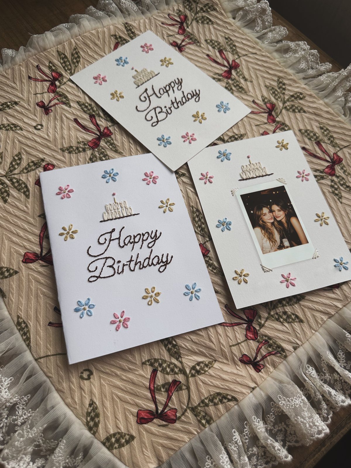 Three white birthday cards with colorful embroidery and one featuring a small photo.