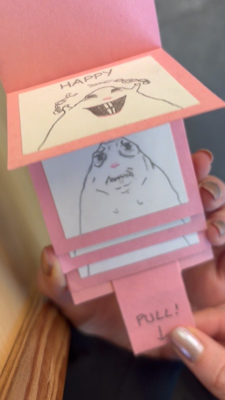 Handmade pink pull-tab birthday card with funny hand-drawn cartoon faces and text.