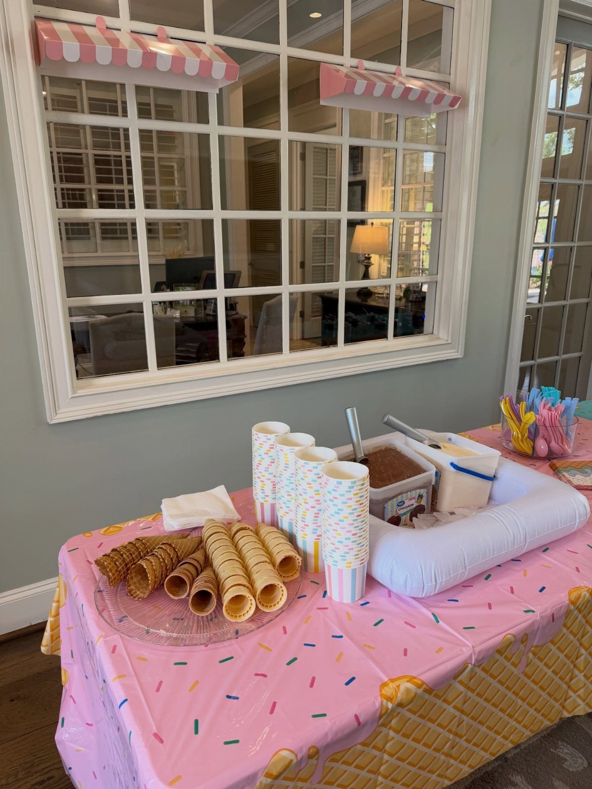 Ice cream buffet setup with waffle cones, colorful cups, and ice cream tubs.